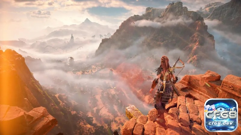 Game Horizon Forbidden West: Cuộc đi săn quái máy khổng lồ Aloy bám tay vào mỏm đá trên vách, bên dưới là tàn tích đổ nát và thảm thực vật dày